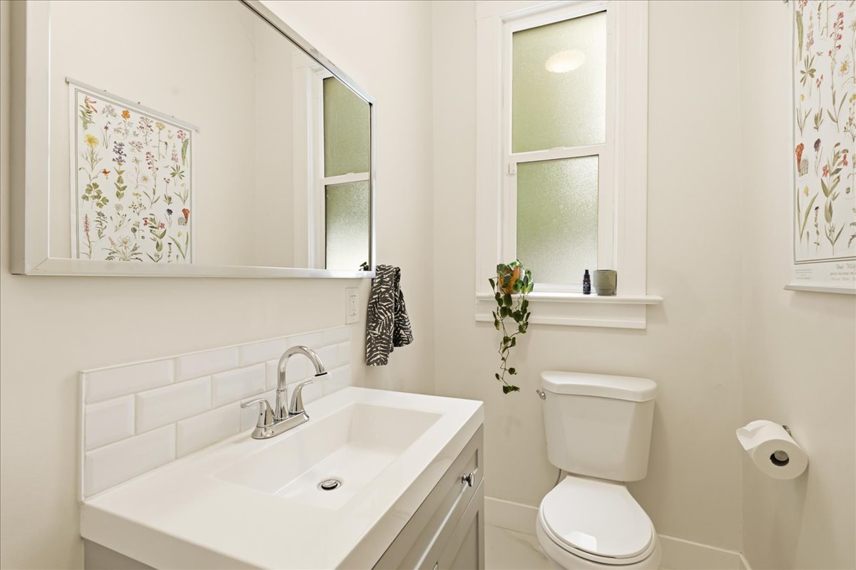 Bathroom vanity featuring an integrated sink, polished chrome faucet, and white subway tile backsplash