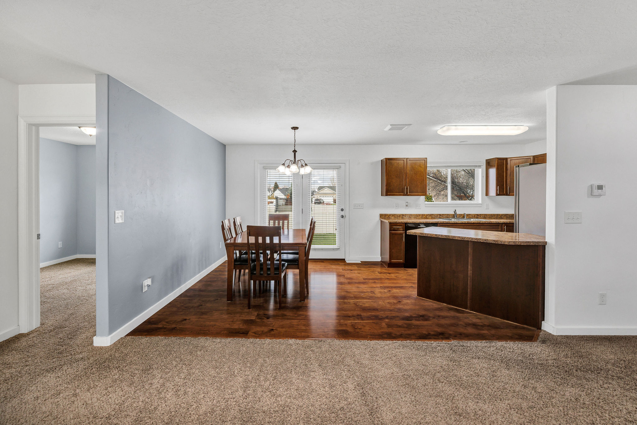 Dining area with wood-finish flooring, featuring a chandelier and patio door