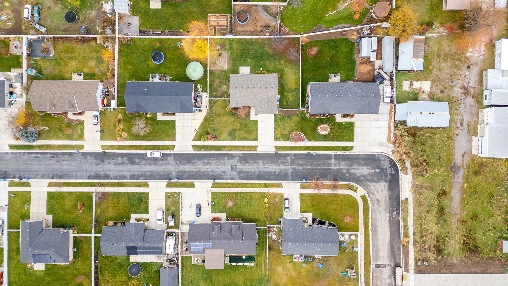 Residential street featuring multiple properties with green lawns and paved driveways