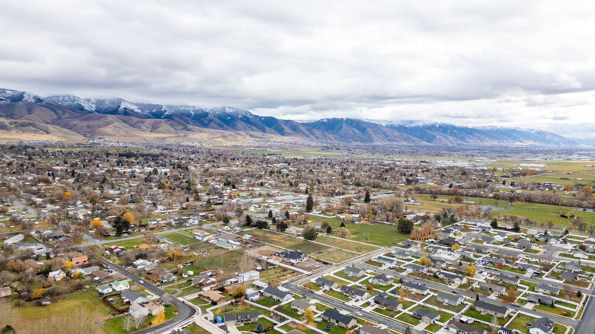 Expansive aerial perspective showcasing a residential community with a backdrop of snow-capped mountains