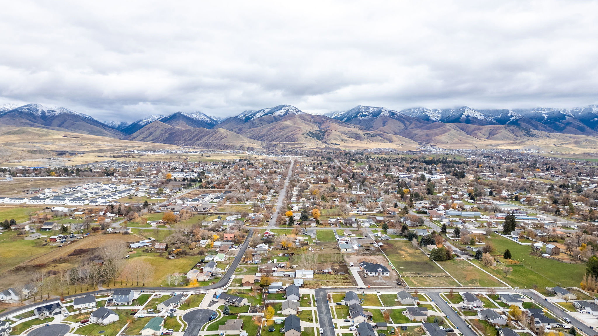 Expansive aerial perspective showcasing a residential community set against a backdrop of snow-capped mountains