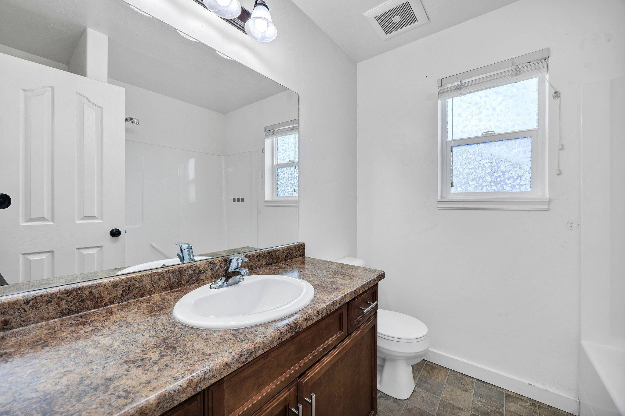 Bathroom featuring a vanity with a laminate countertop, integrated sink, and wood-finish cabinetry
