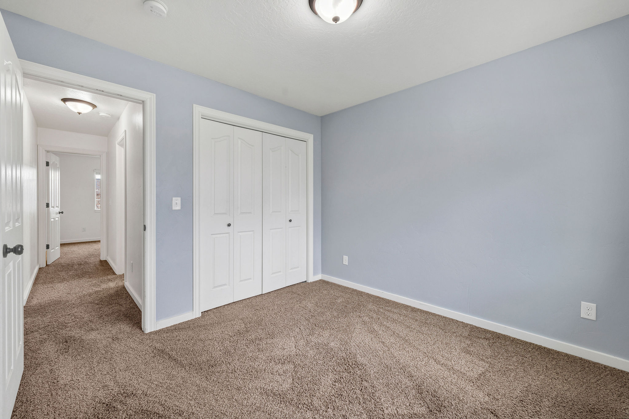 Carpeted room with light blue wall paint, white trim, and a ceiling-mounted light fixture