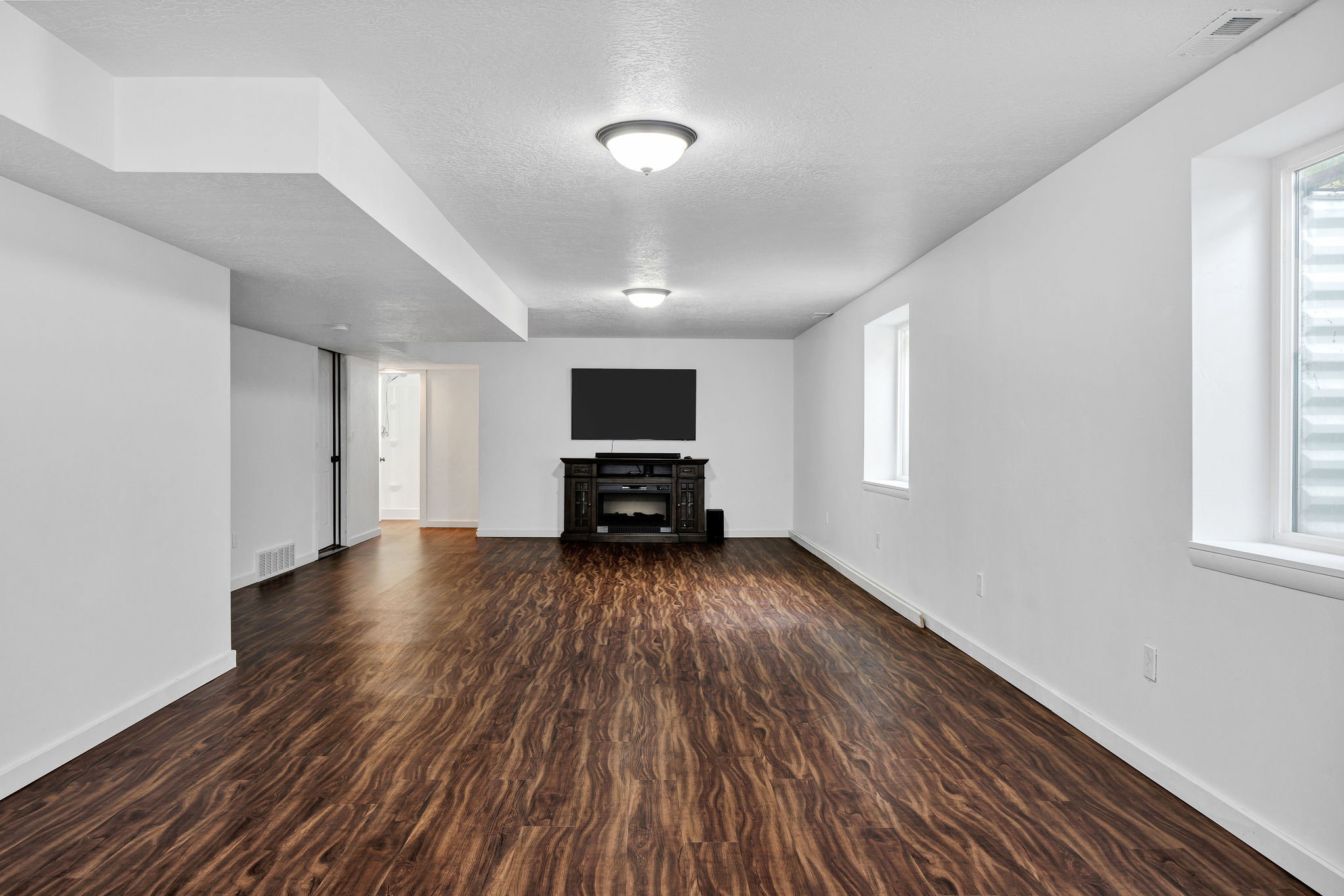 Spacious room featuring wood-finish flooring, white walls, and recessed lighting