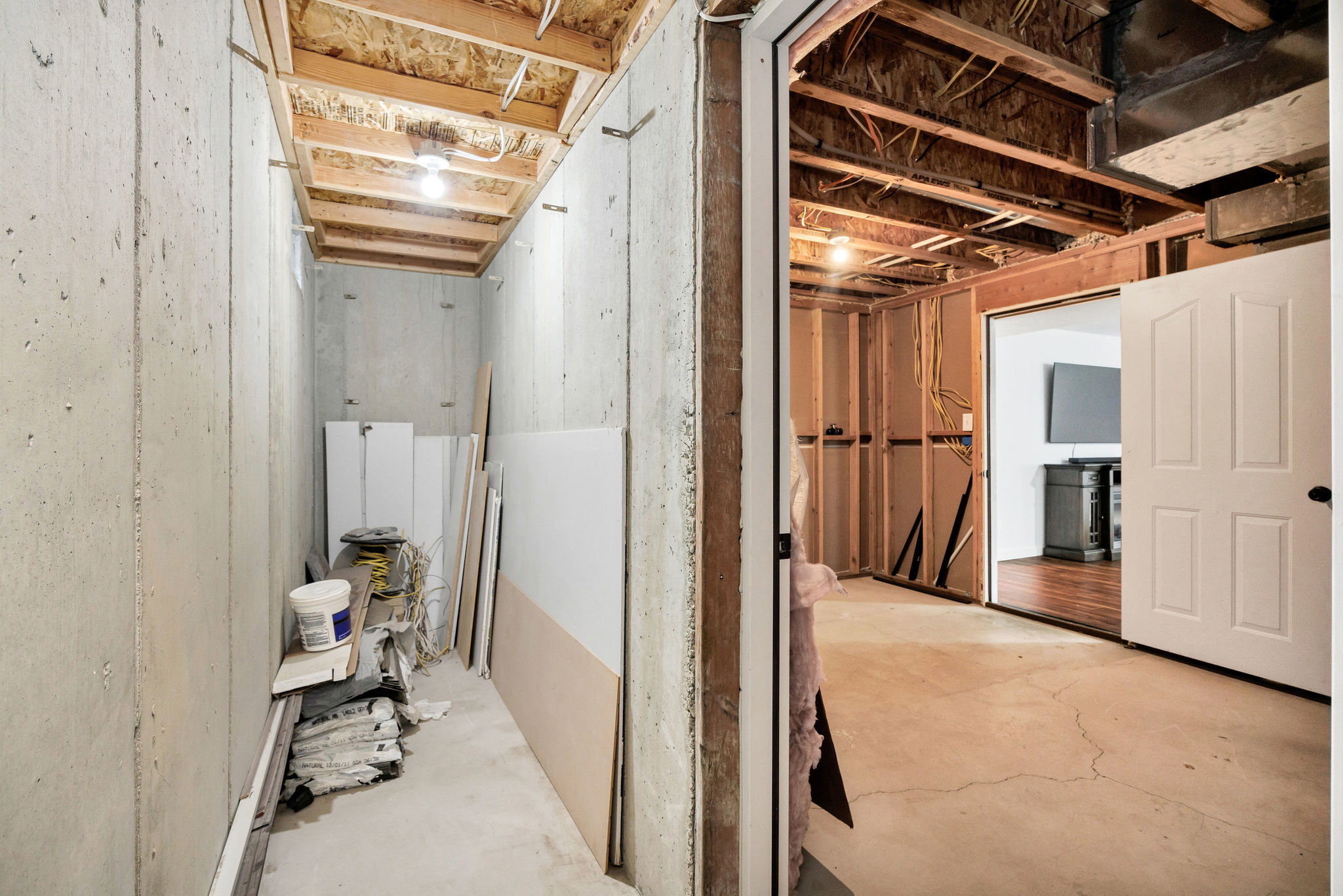 Unfinished basement area featuring concrete walls and flooring, exposed ceiling joists, and a partial wood-framed wall