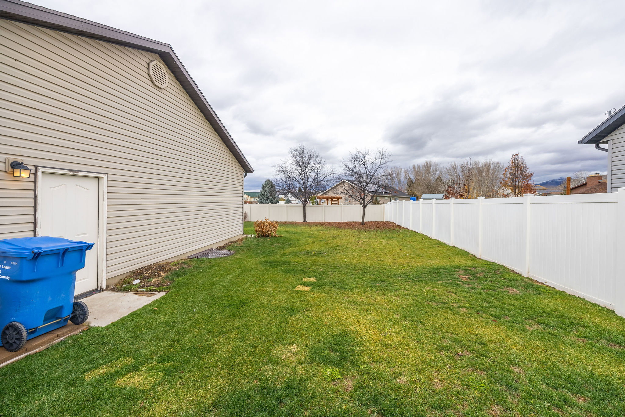 Expansive grassy yard with a white privacy fence