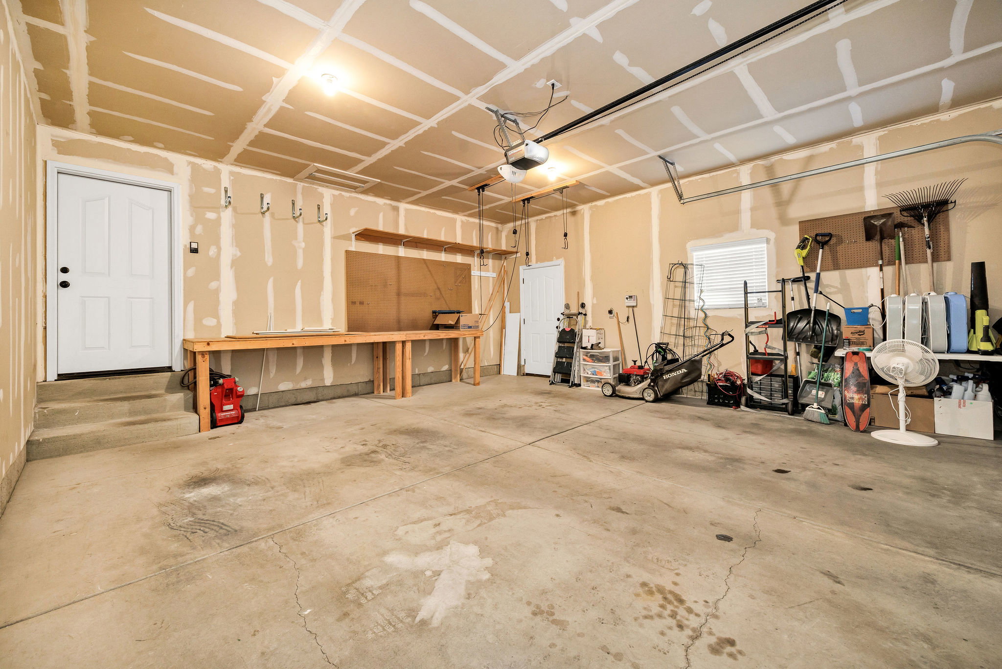 Spacious garage with concrete flooring and exposed drywall
