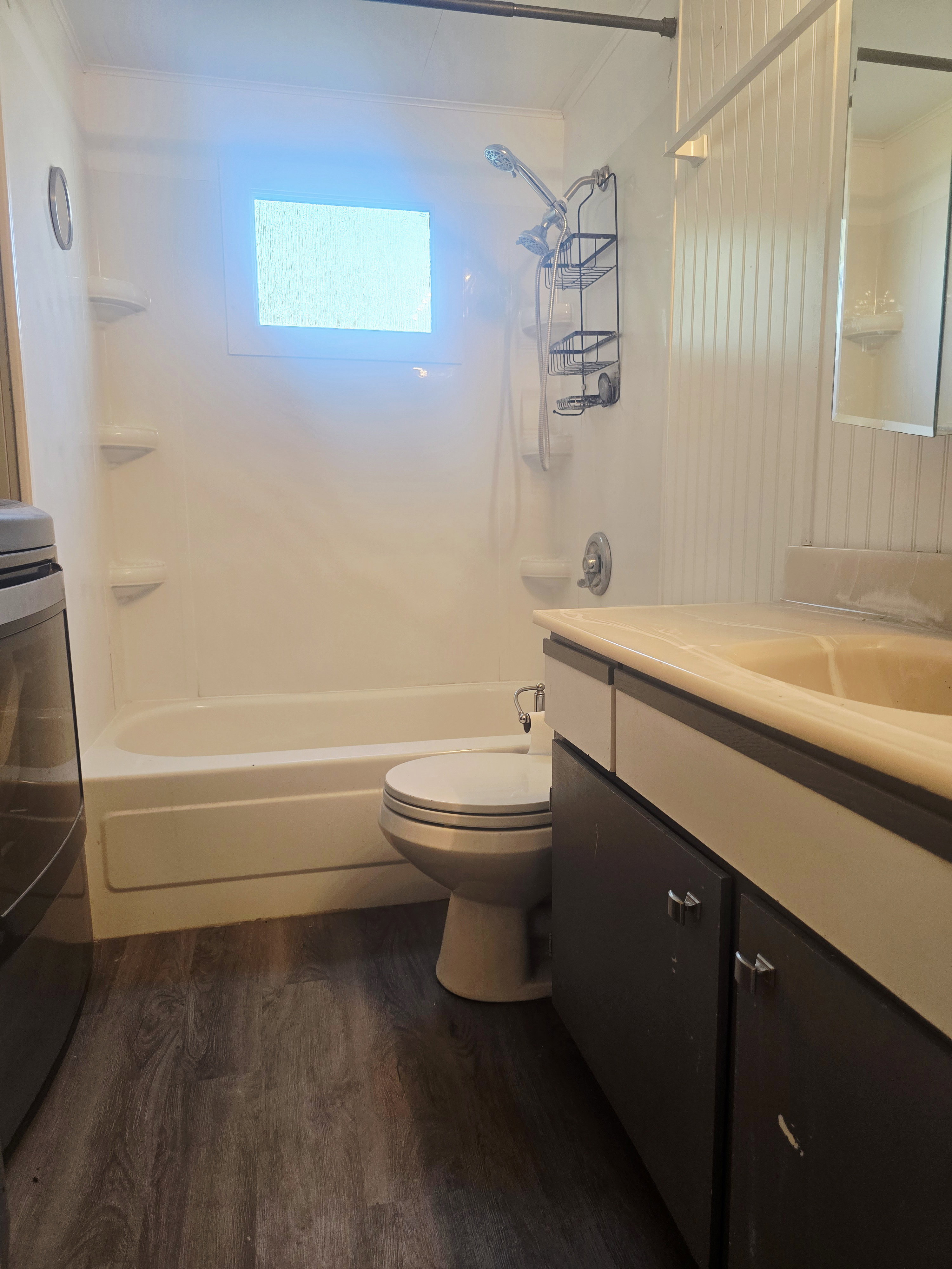 Bathroom featuring a white tub/shower combination, dark wood-finish flooring, a toilet, and a vanity with an integrated sink