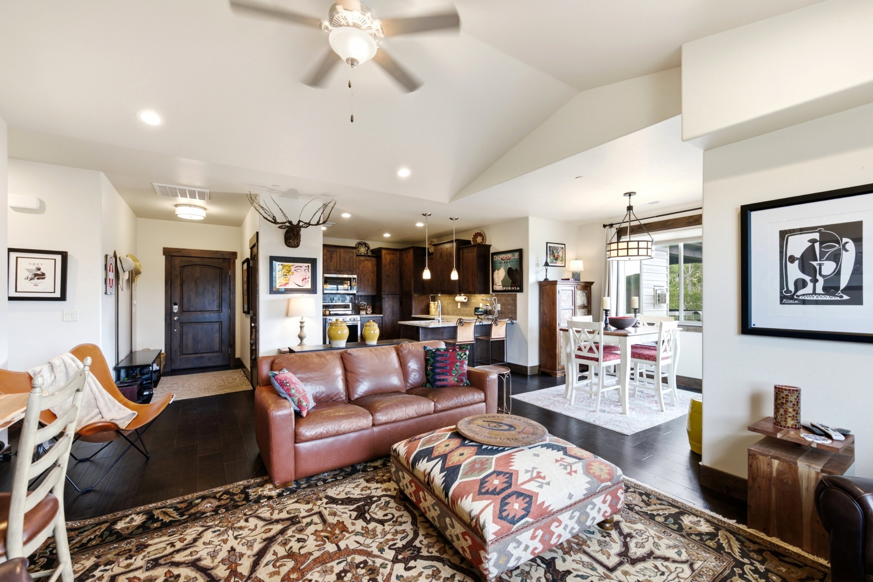Open-concept living area featuring vaulted ceilings, dark wood-finish flooring, recessed lighting, and a ceiling fan