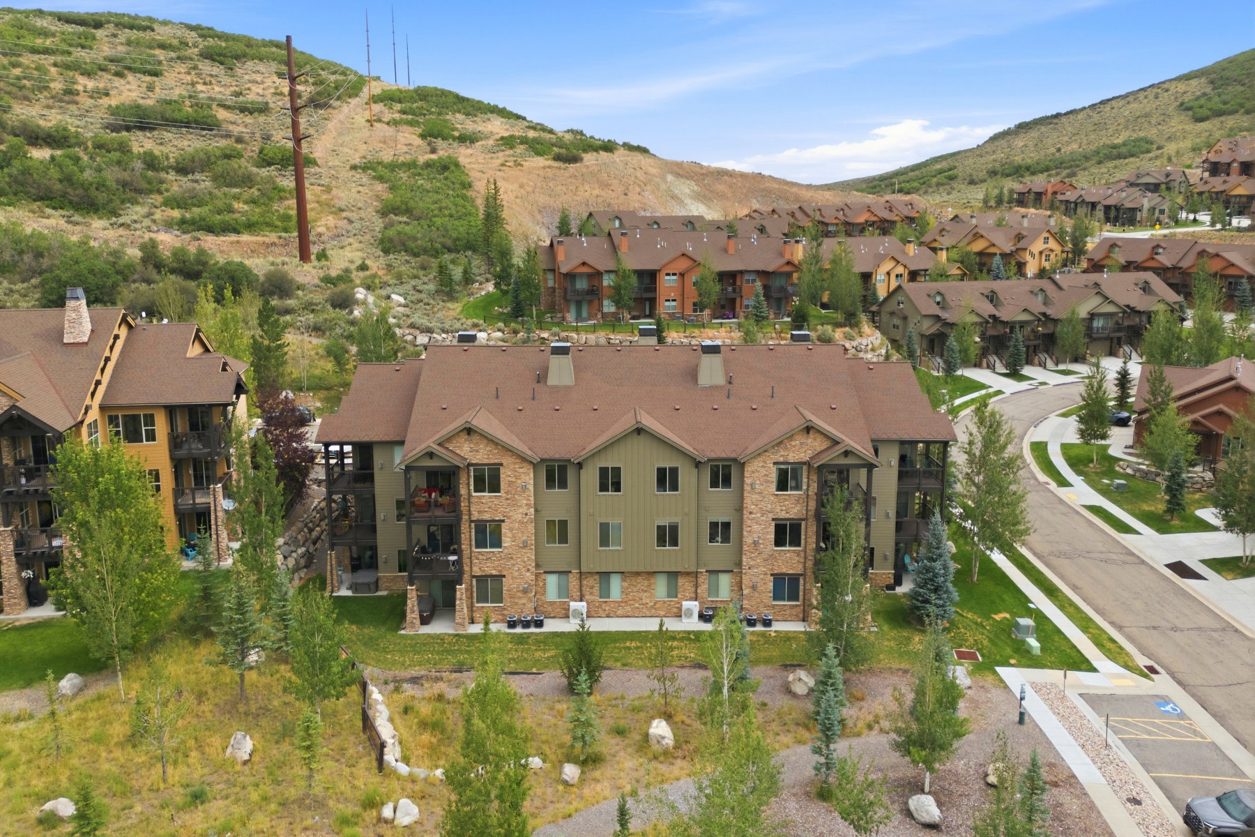 Multi-story residential building featuring a stone and siding exterior, multiple balconies, and a brown shingle roof