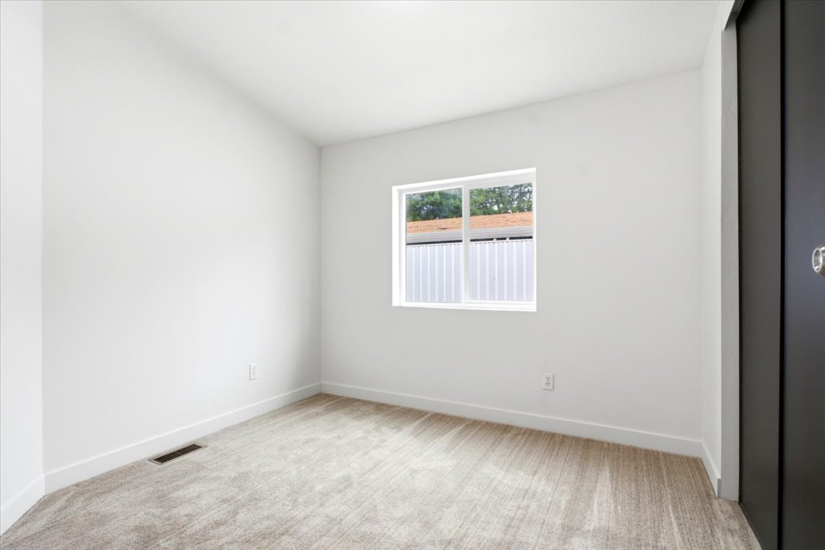Bright room featuring light-toned carpet, white walls, and a white window frame