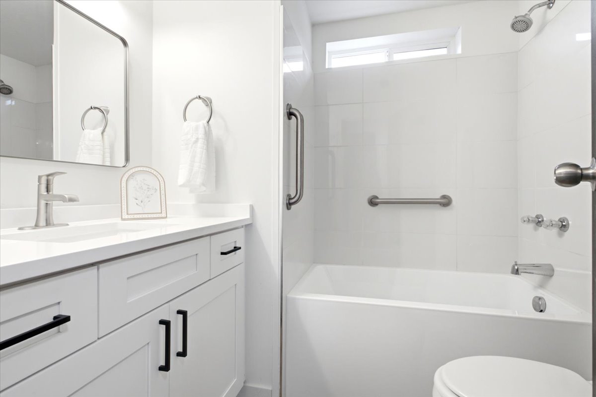 Bathroom featuring a white vanity with black hardware, a rectangular undermount sink, and a white countertop
