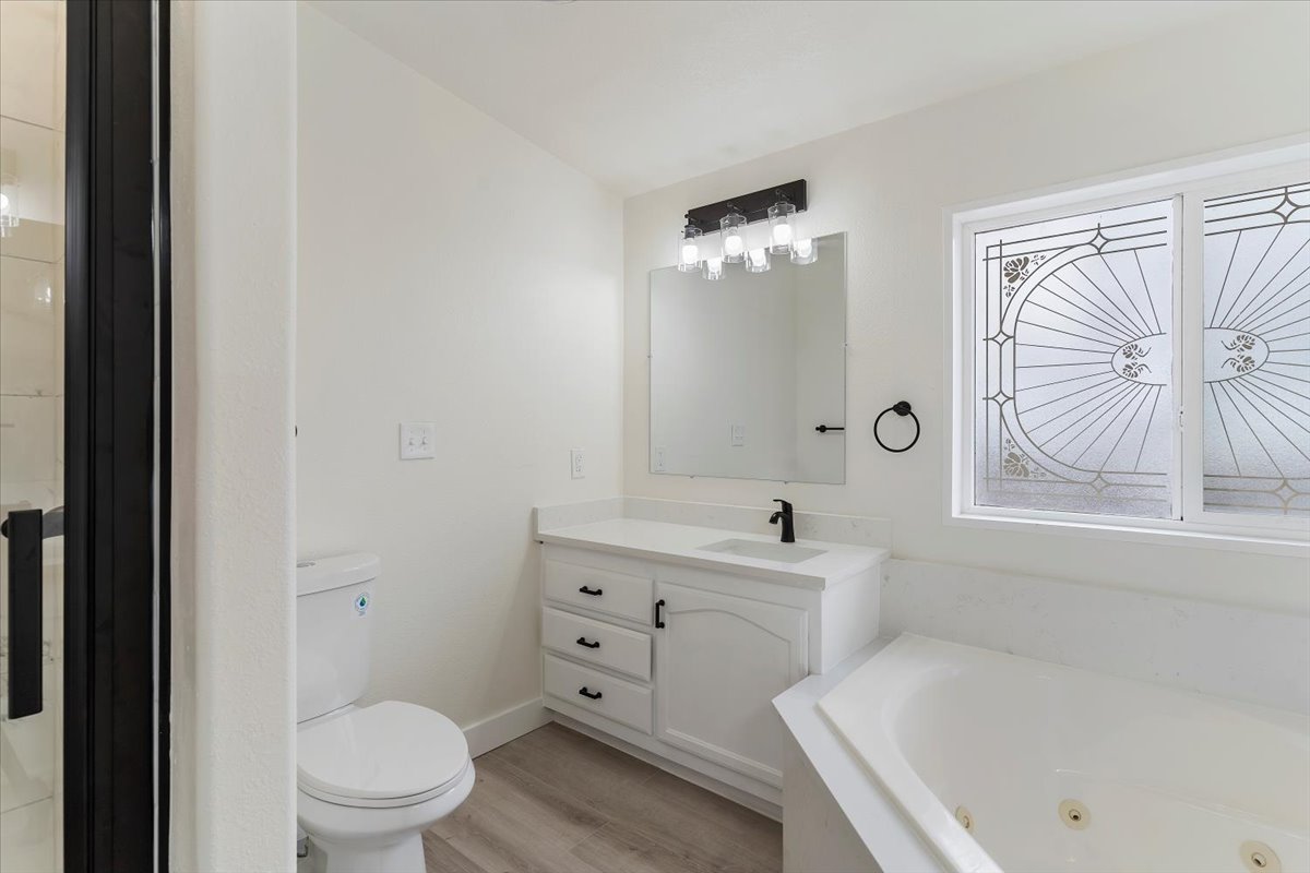 Bathroom featuring a white vanity with a single sink, black hardware, and an overhead light fixture