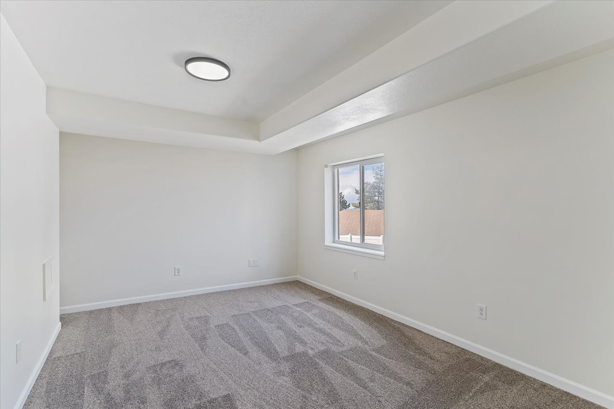 Room featuring gray patterned carpeting, a white window frame, and a flush-mount ceiling light fixture
