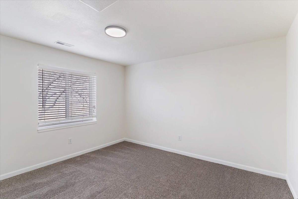 Carpeted room featuring a single window with horizontal blinds, a flush-mount ceiling light fixture, and white wall finishes