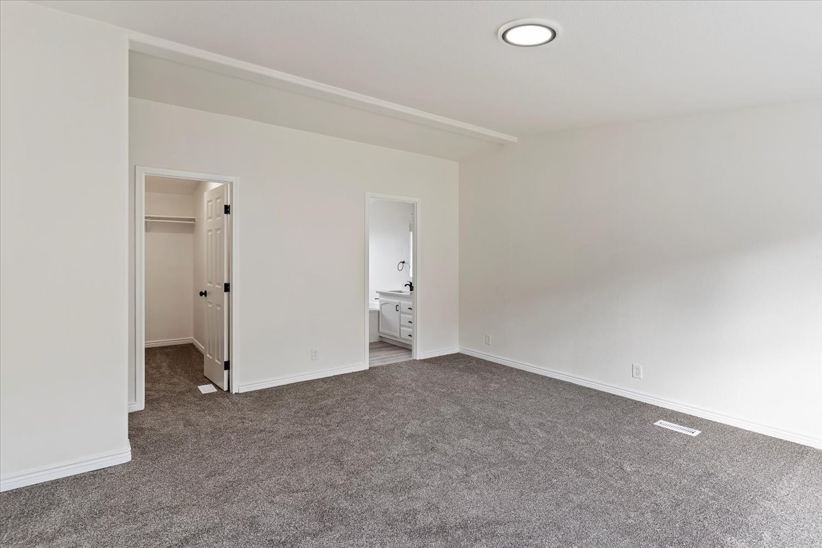 Spacious room featuring gray carpeting, white walls, and a recessed ceiling light