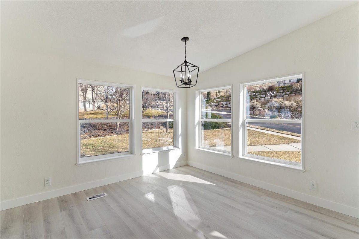 Bright room featuring vaulted ceilings, a contemporary geometric chandelier, and wood-finish flooring