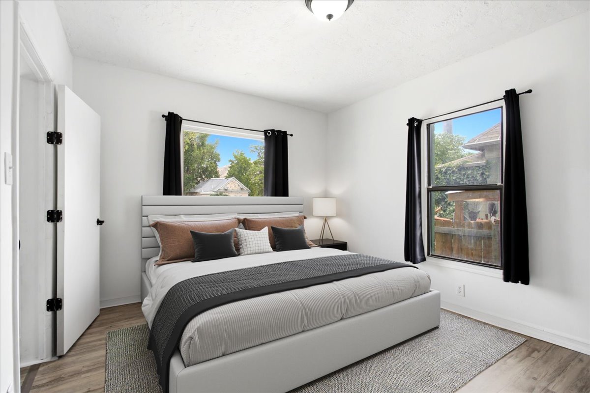 Room featuring white walls, wood-finish flooring, and multiple windows