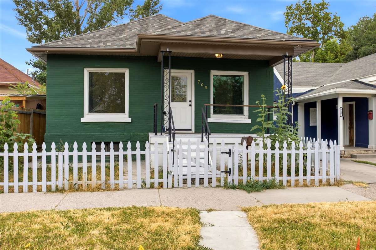 Exterior facade featuring a covered porch, green brick siding, and white window trim