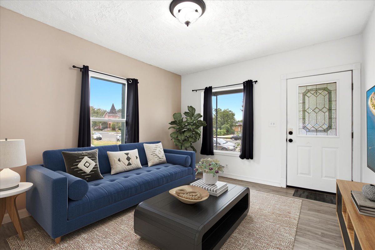 Bright living area featuring wood-finish flooring, light-toned walls, and a white entry door with decorative glass