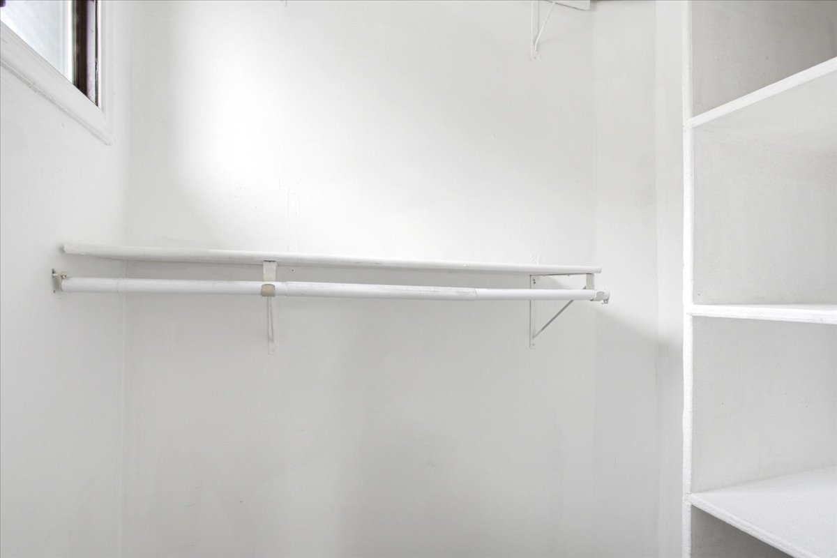 White closet space featuring a window, built-in shelving, and a double hanging rod system