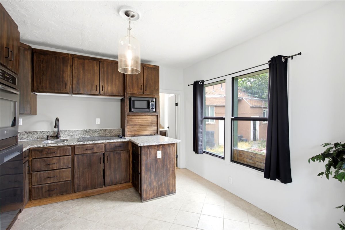 Well-appointed kitchen featuring dark wood cabinetry, light-colored stone-finish countertops, and a built-in microwave