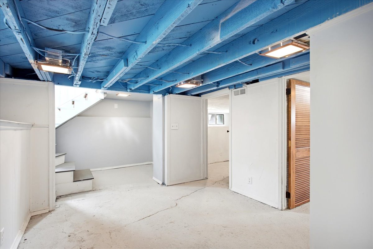 Finished lower level space with exposed joist ceiling, concrete flooring, recessed lighting, and white paneled walls