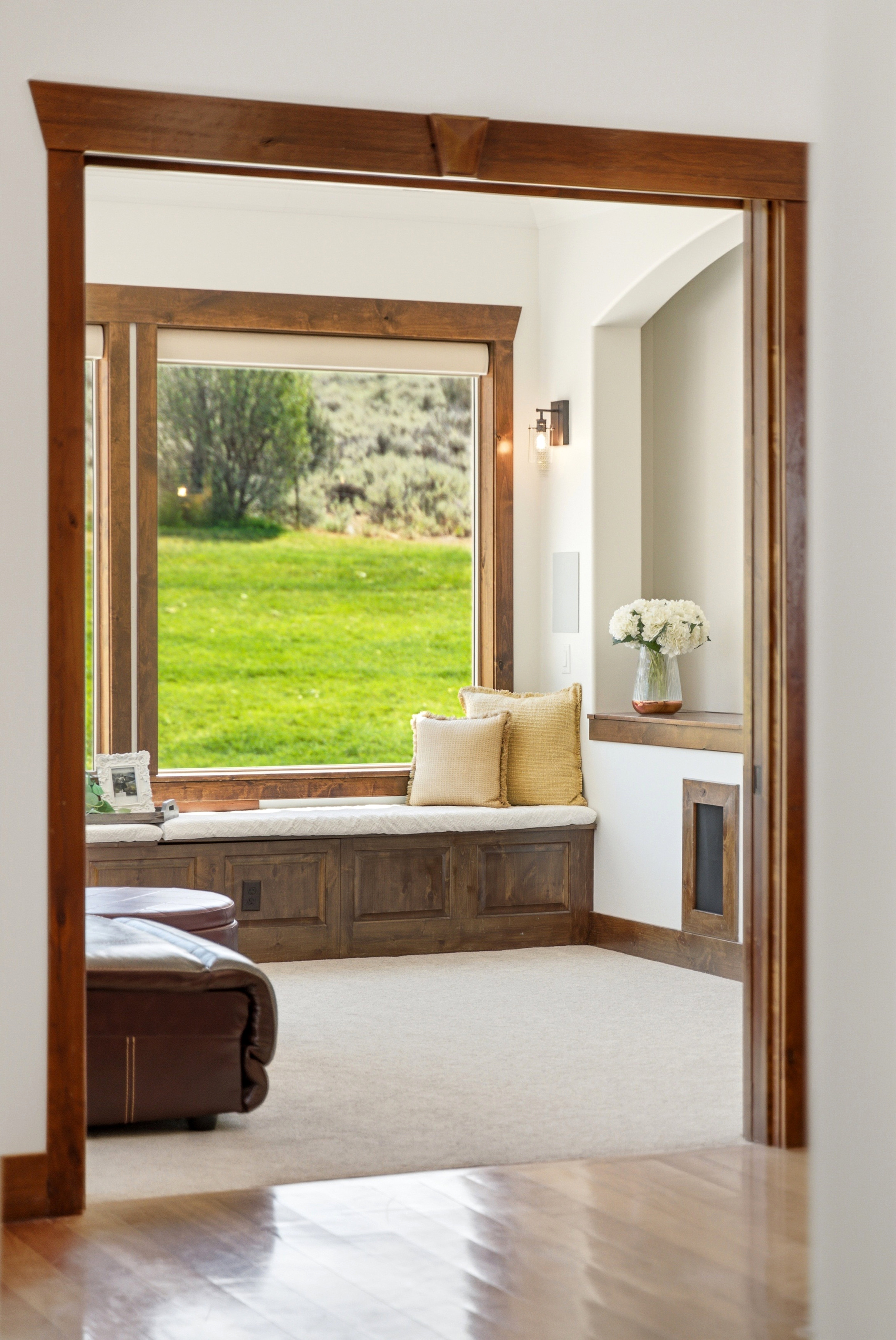 Built-in window seat with storage, framed by dark wood trim, offering expansive outdoor views