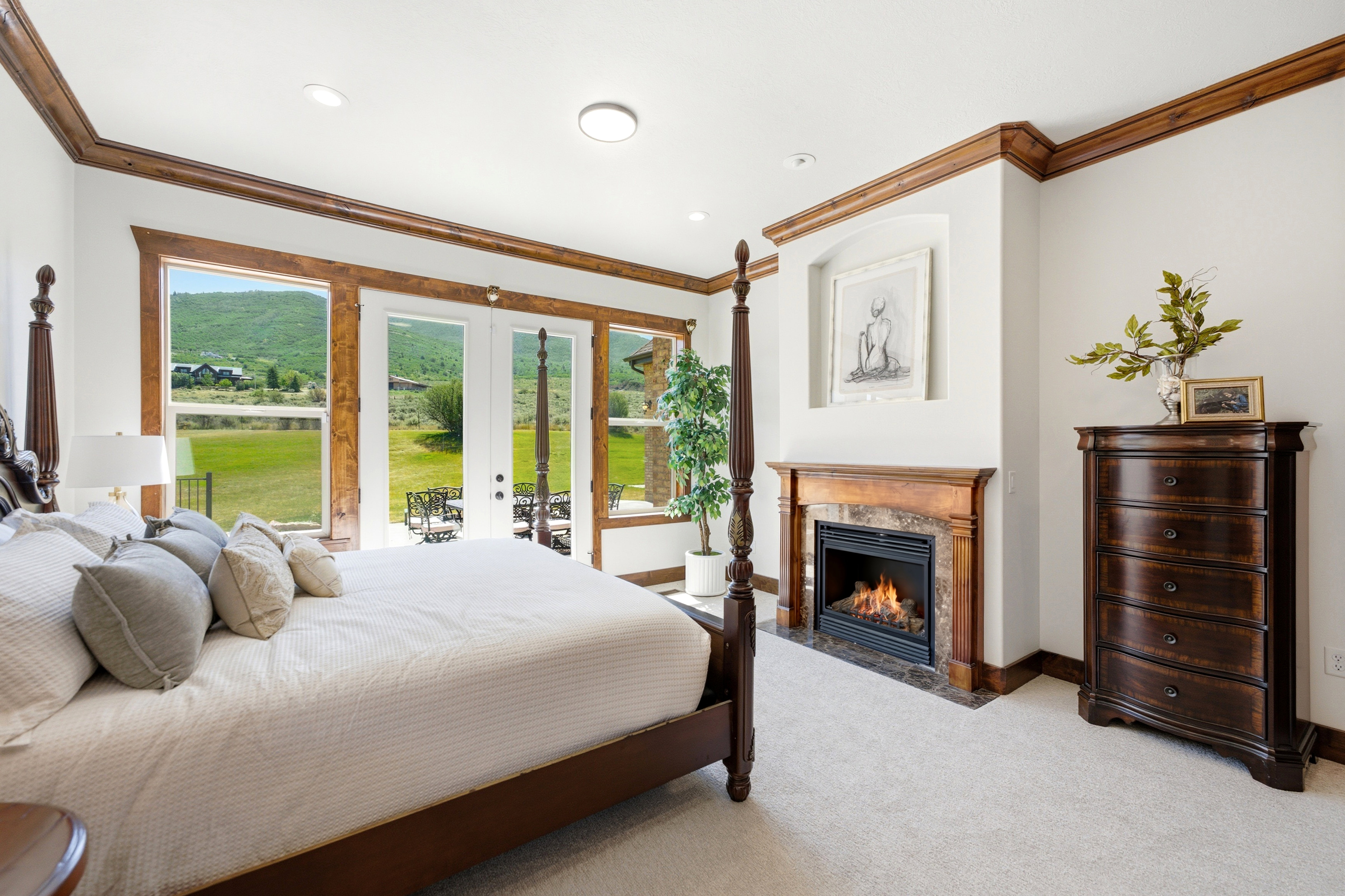 Bedroom featuring a built-in fireplace with a stone surround and wood mantel, large windows, and glass doors opening to the exterior