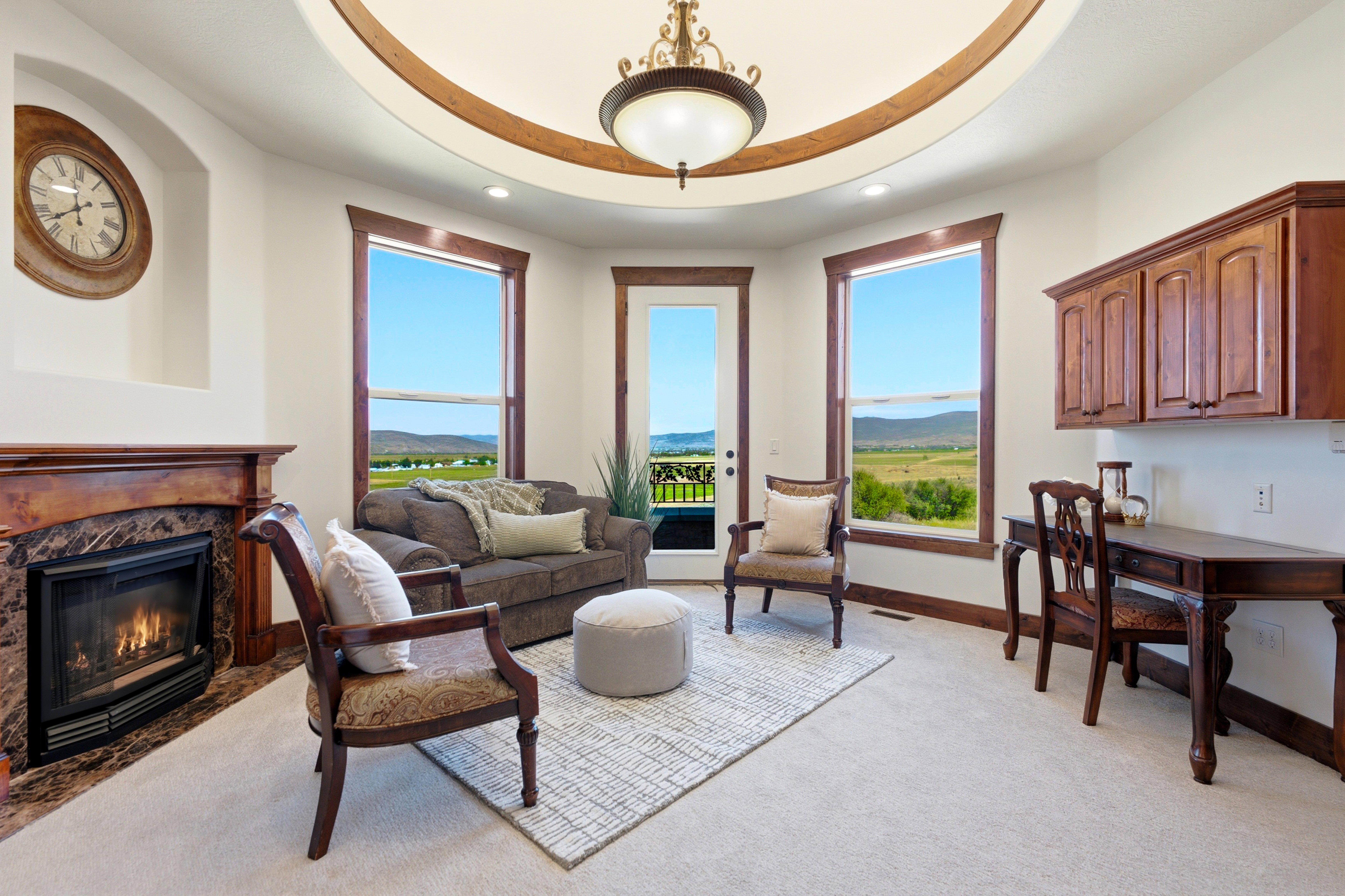 Living area featuring a tray ceiling with wood trim, a central chandelier, and recessed lighting