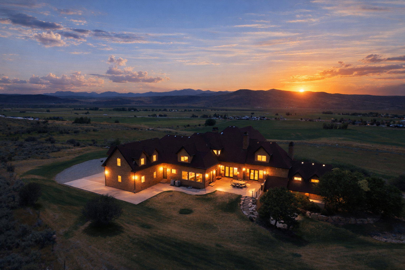 Expansive property featuring a multi-level residence with a dark roof and numerous illuminated windows