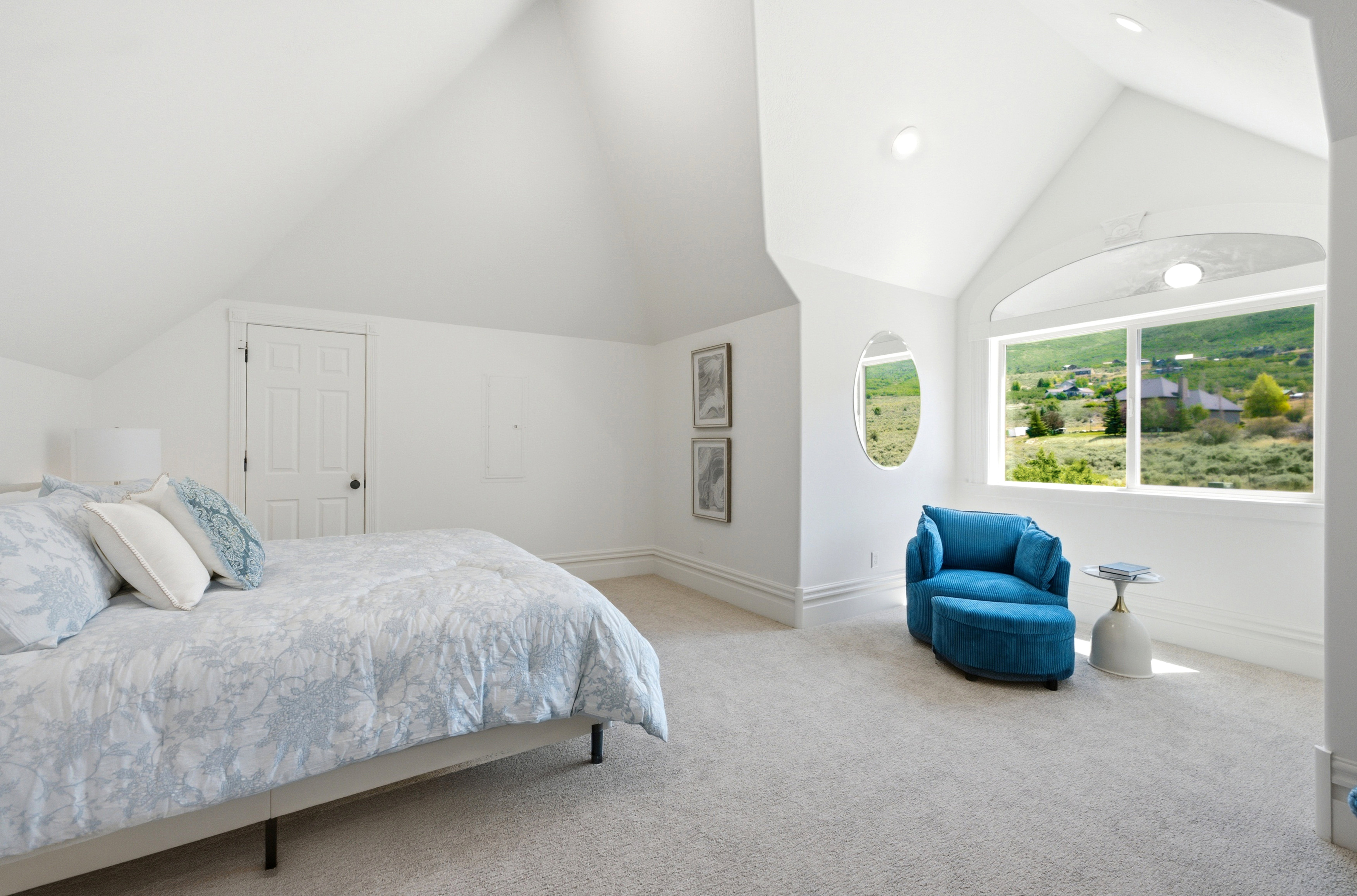 Vaulted white ceilings featuring recessed lighting, a large picture window, and a secondary oval window