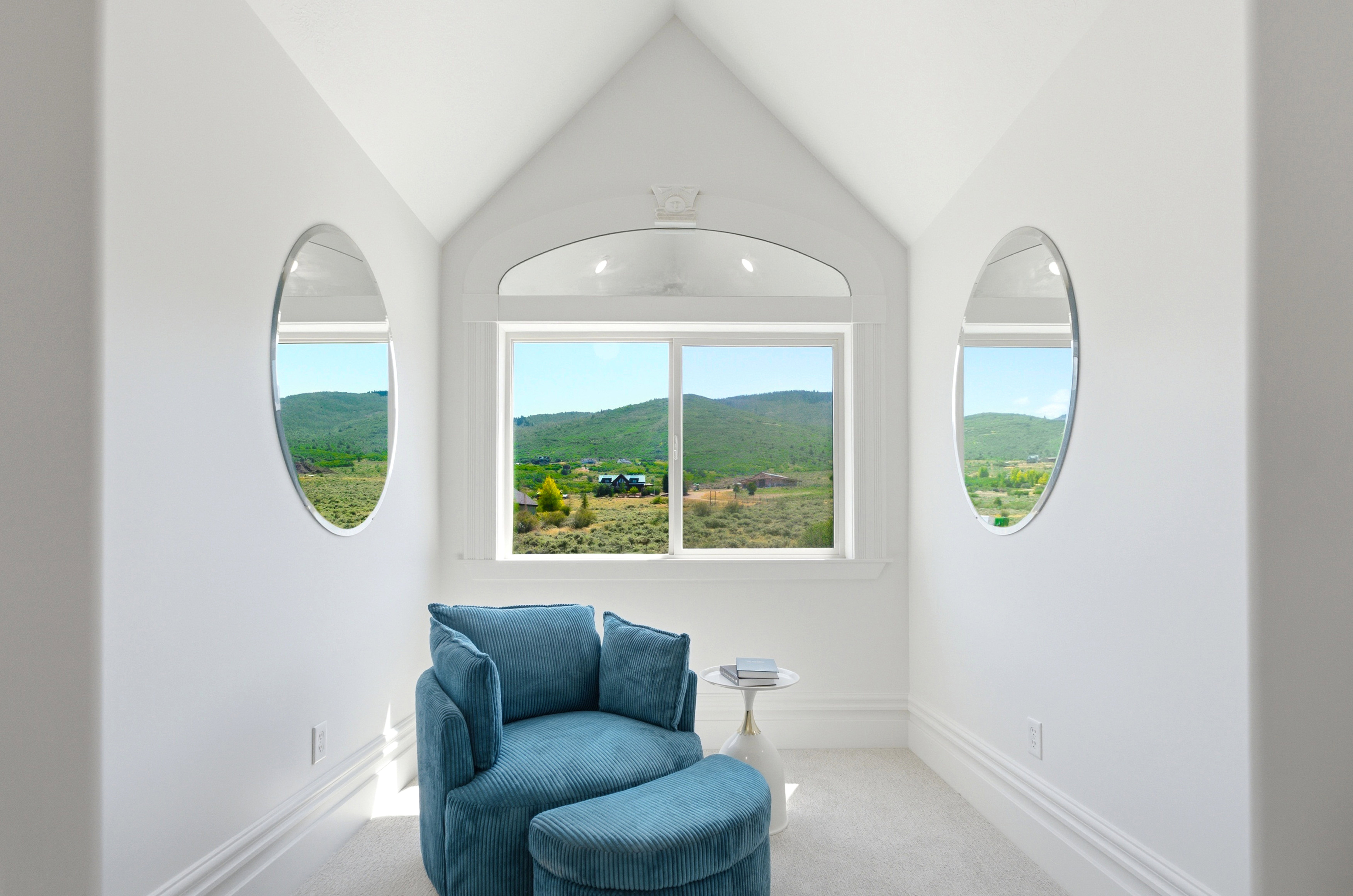 Recessed window alcove featuring a large rectangular window and two oval windows, framed by bright white trim and baseboards