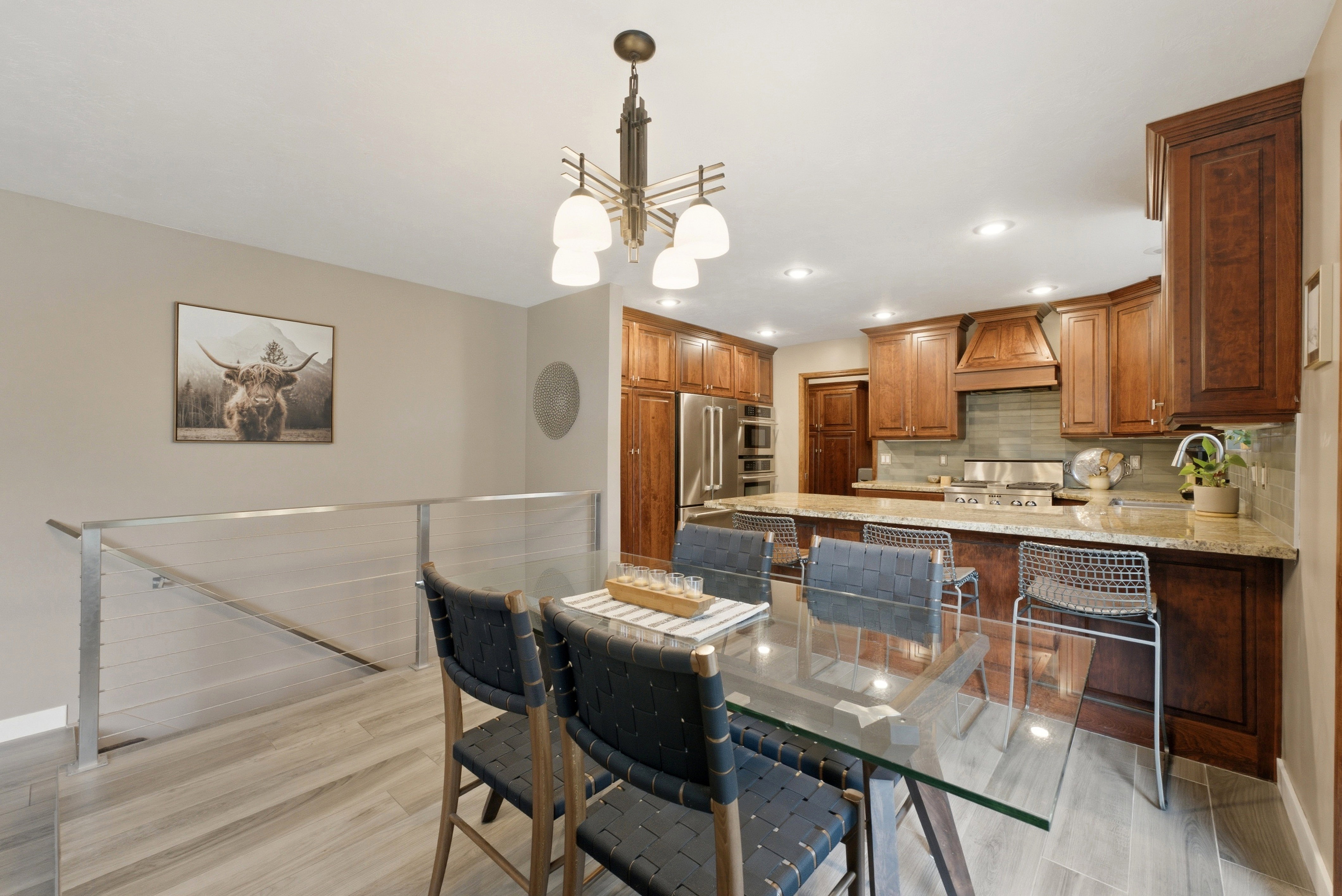 Open-concept kitchen and dining area featuring warm wood cabinetry, stainless steel appliances, a tile backsplash, and a granite countertop island with seating.