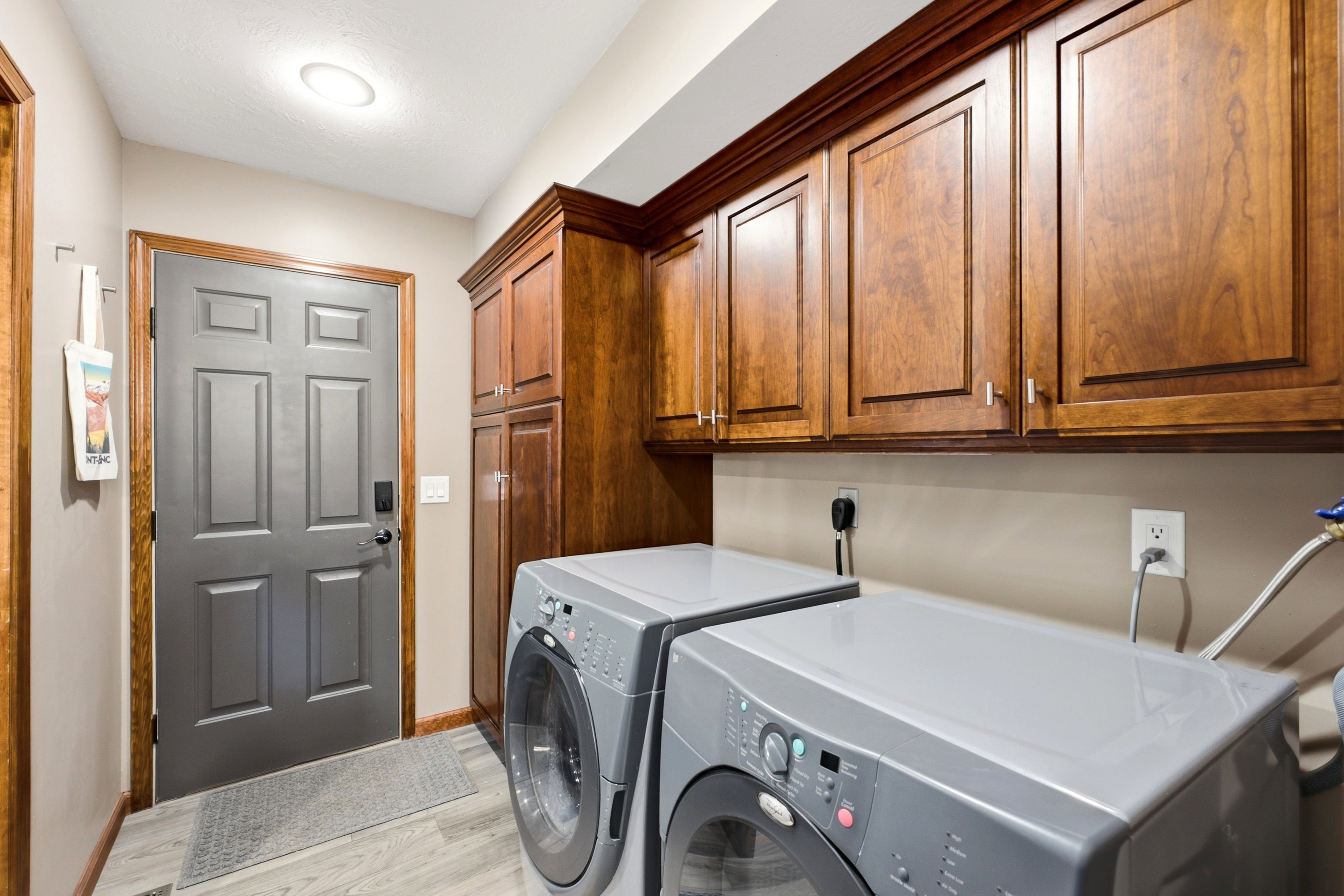 Dedicated laundry area on main level featuring wood-finish cabinetry, built-in storage, and light wood-finish flooring.