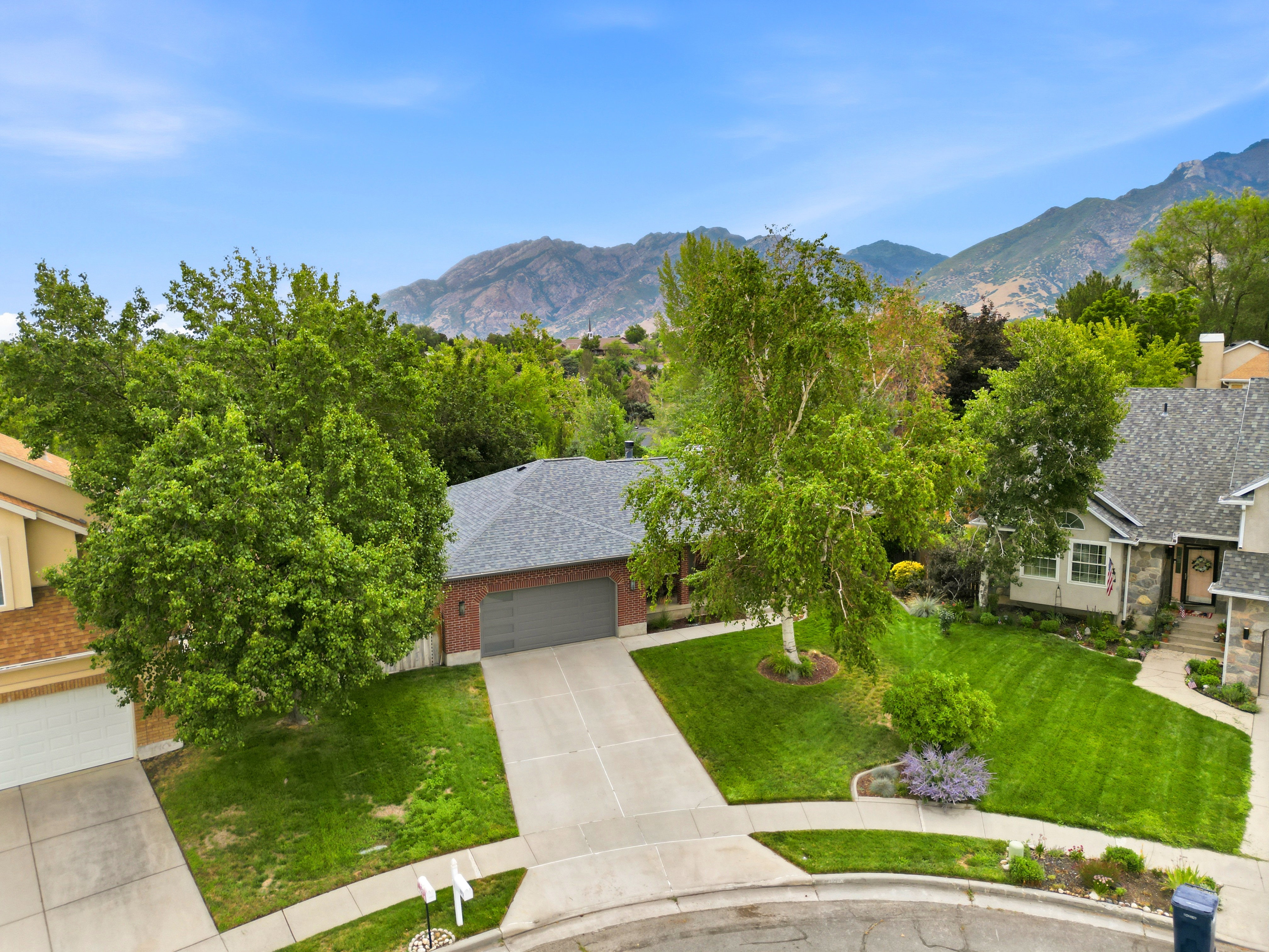 Brick exterior home with an attached garage, newer shingle roof, and a paved driveway