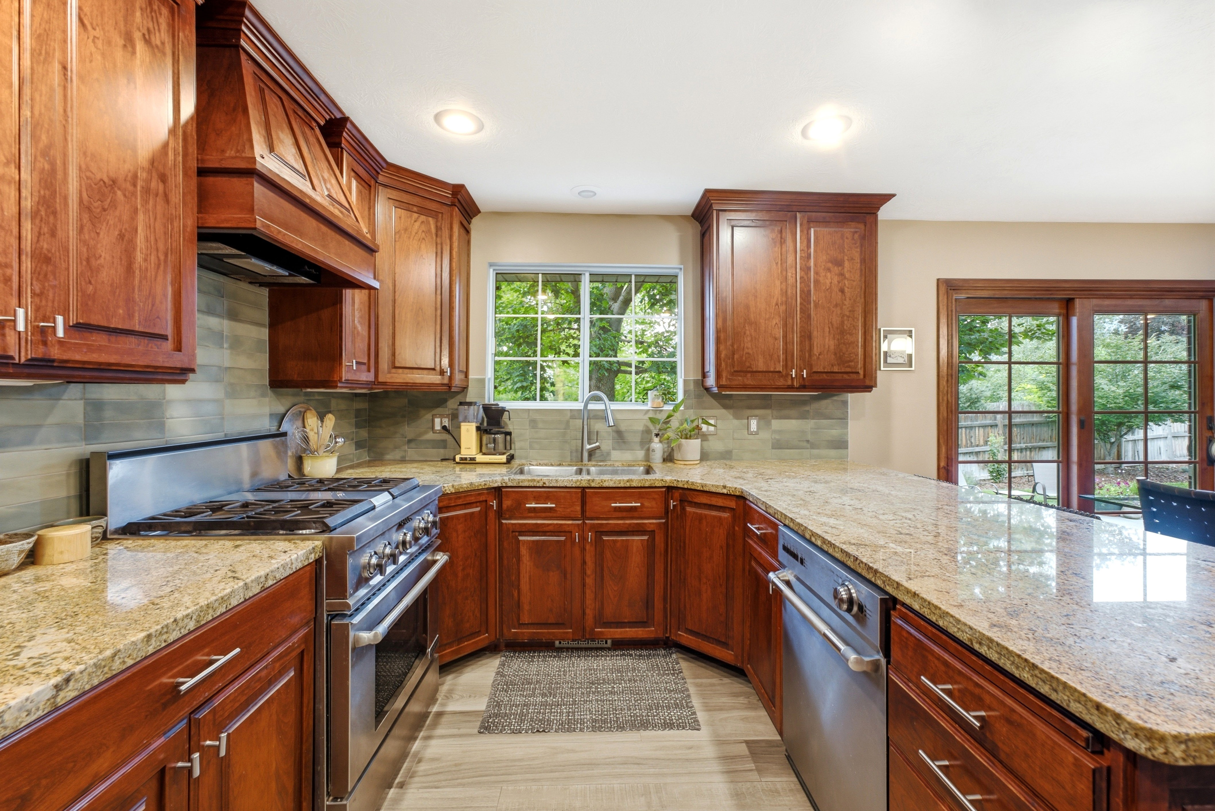 Kitchen featuring rich wood cabinetry, granite countertops, stainless steel appliances (all Jenn-air), a tiled backsplash, and recessed lighting.