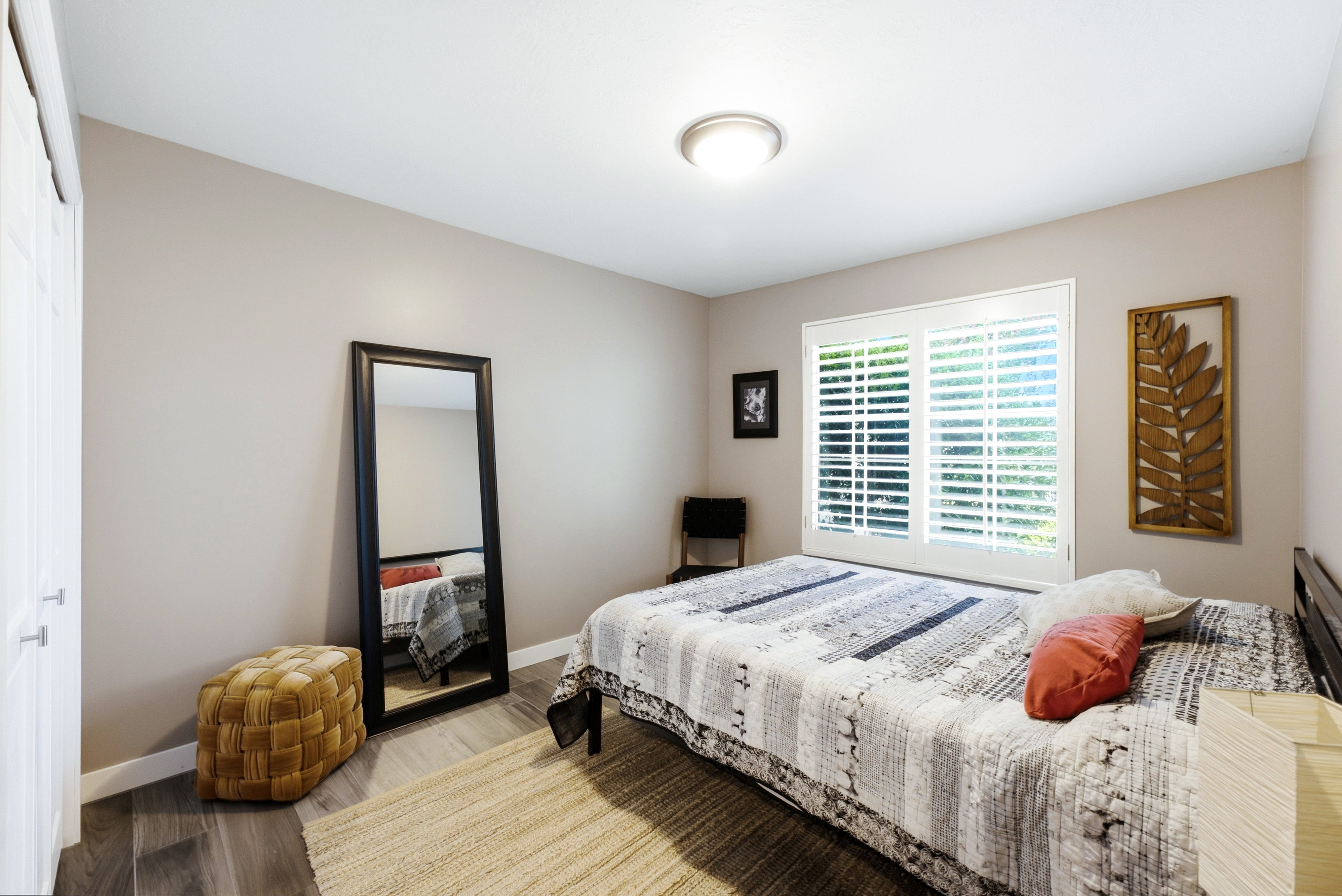 Bedroom featuring wood-finish flooring, neutral wall tones, and white plantation shutters