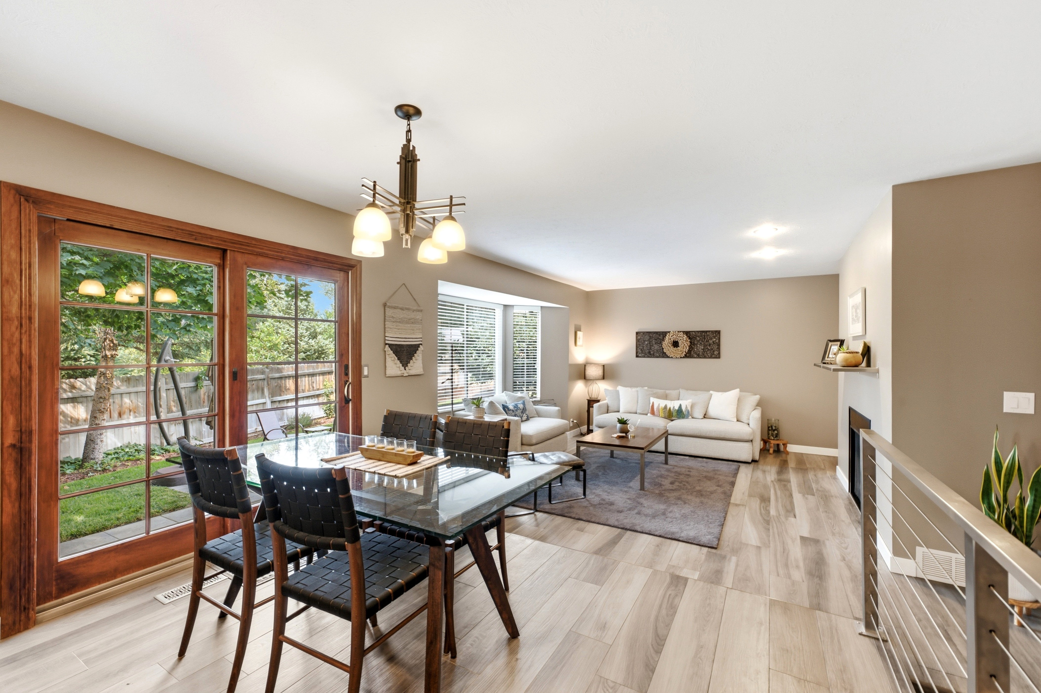 Open-concept living area featuring light wood-finish flooring, a contemporary fireplace with a floating mantel, and abundant natural light from multiple windows.