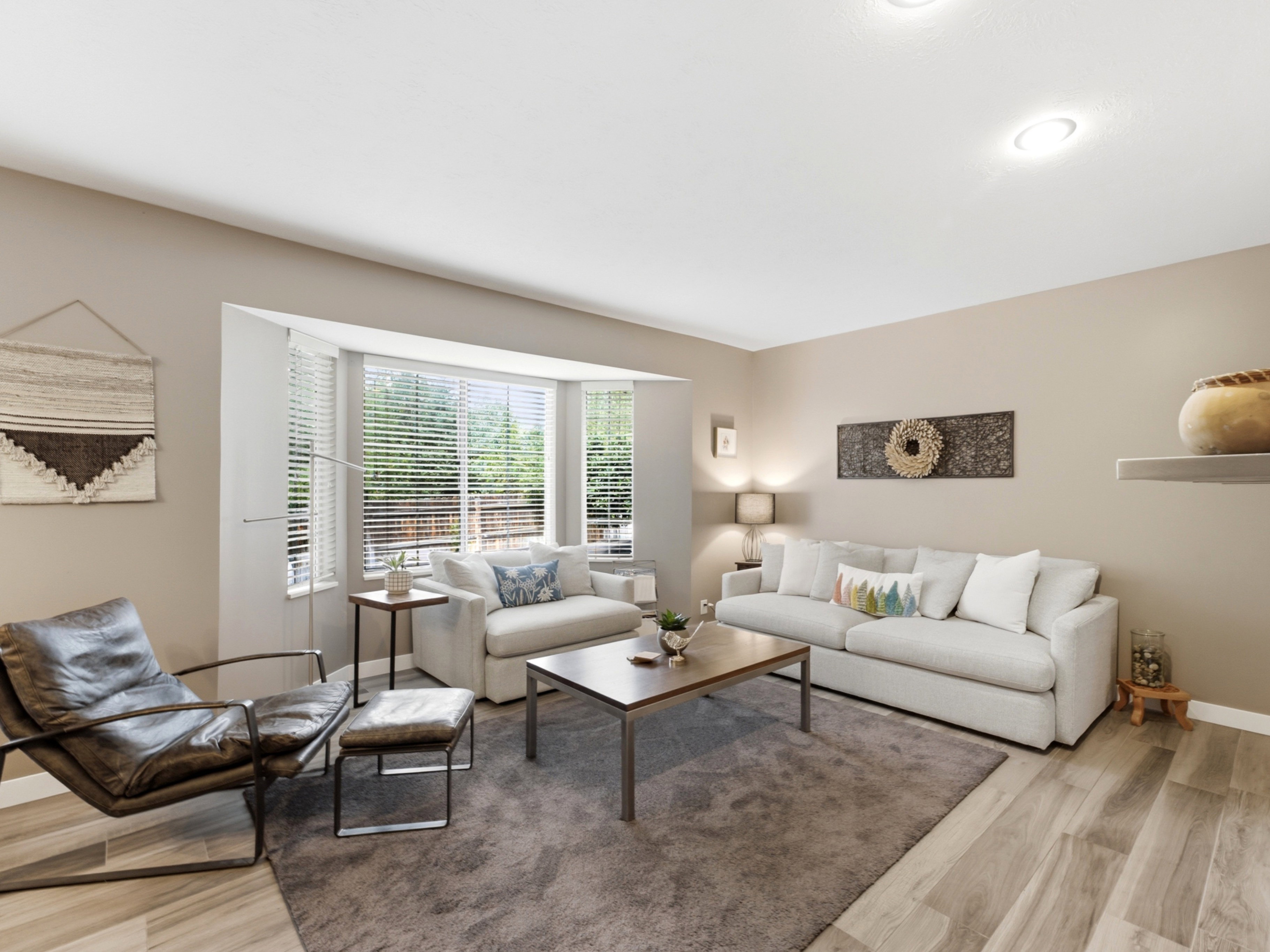Living area featuring wood-finish flooring, neutral wall tones, recessed lighting, and a bay window.