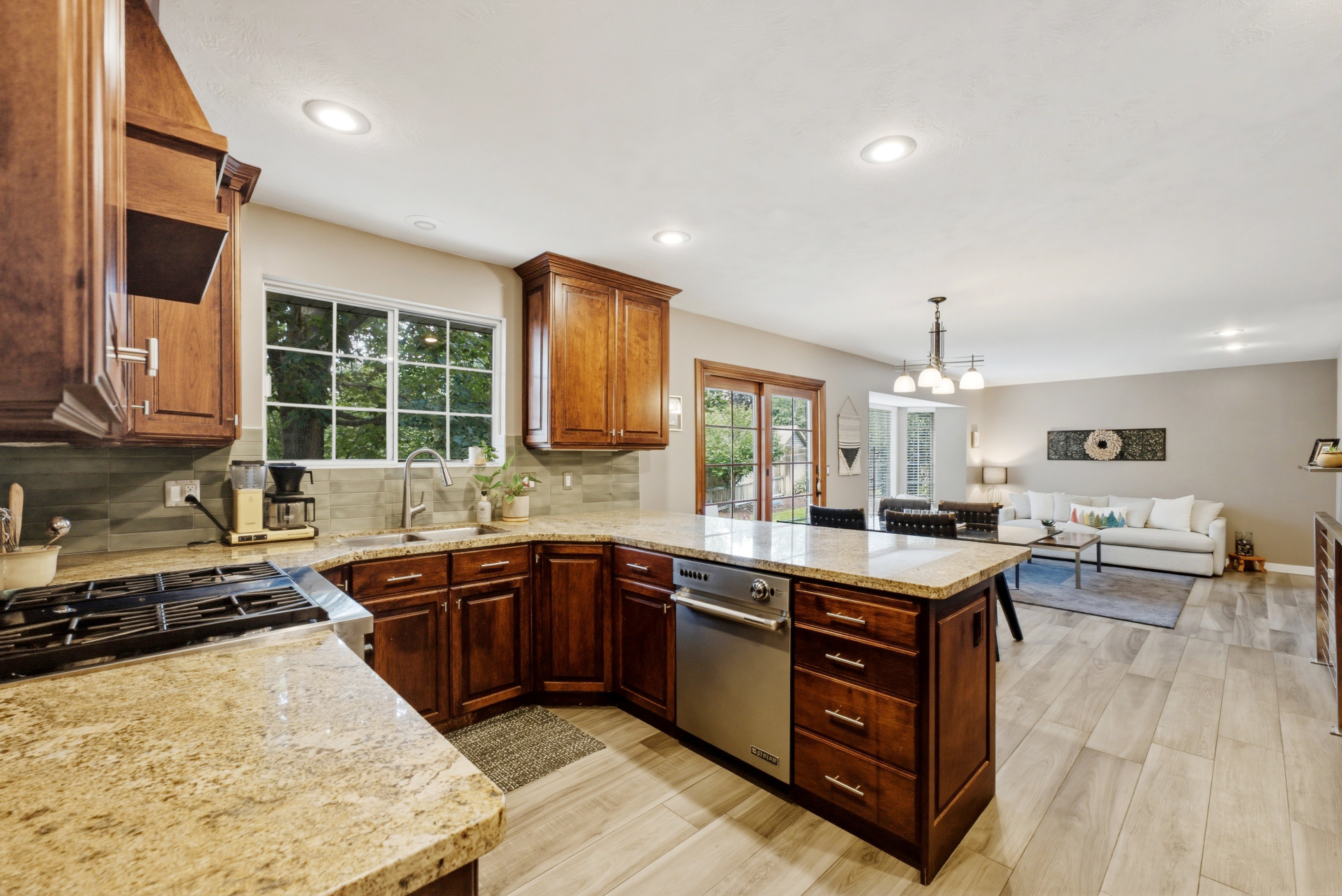 Kitchen featuring wood cabinetry, light-toned countertops, a gas range, and a built-in dishwasher