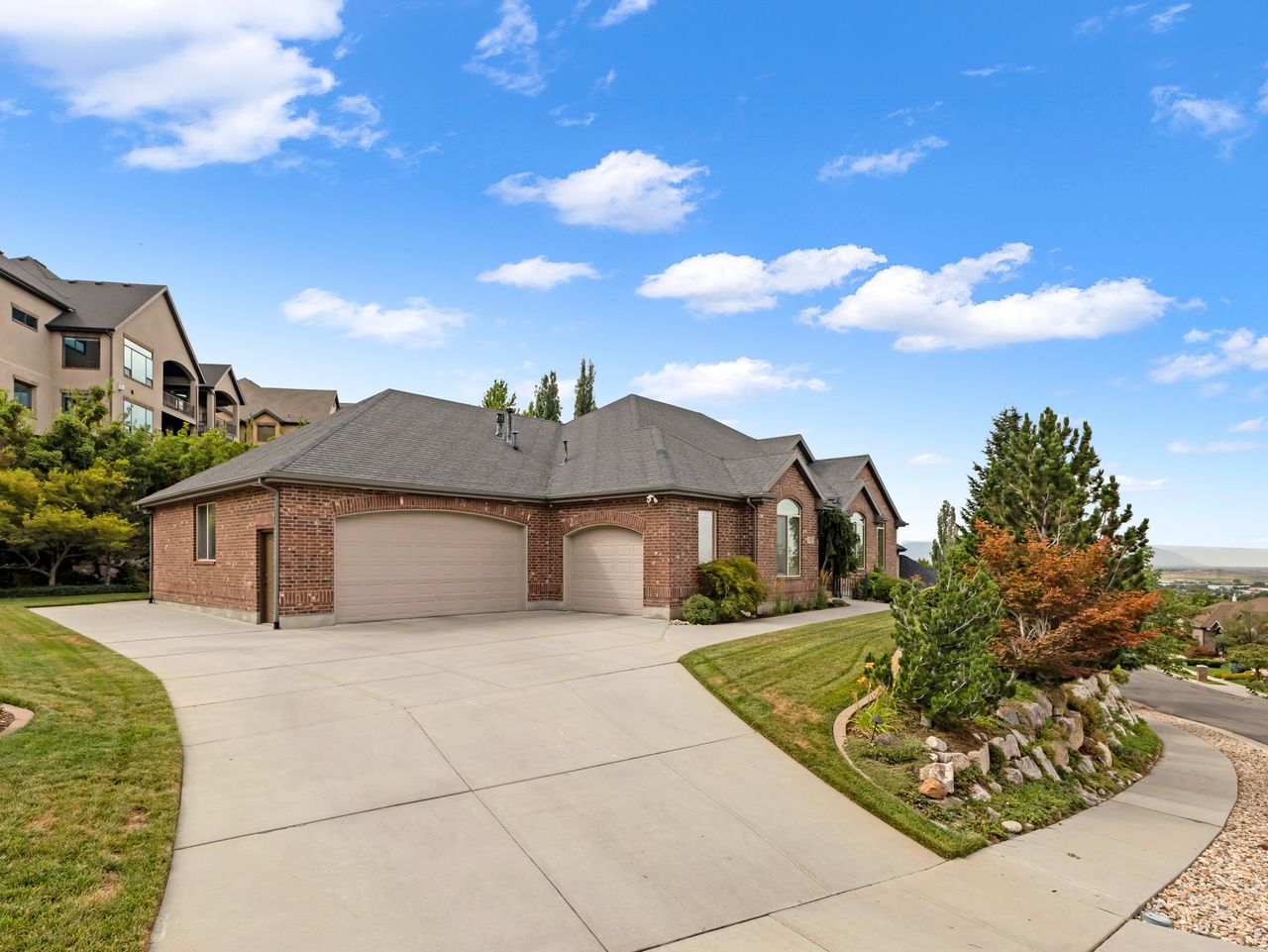 Brick exterior featuring a multi-car garage with arched doors, a concrete driveway, and a shingled roof