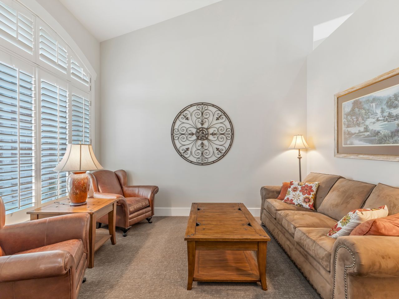 Living area featuring vaulted ceilings, a large arched window with custom plantation shutters, and light-colored wall paint
