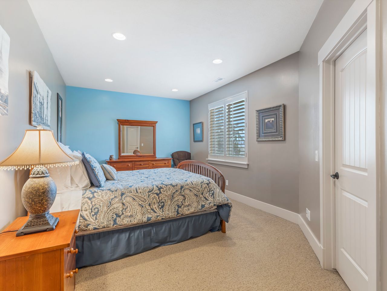 Carpeted bedroom featuring a window with plantation shutters, recessed ceiling lighting, and a paneled interior door