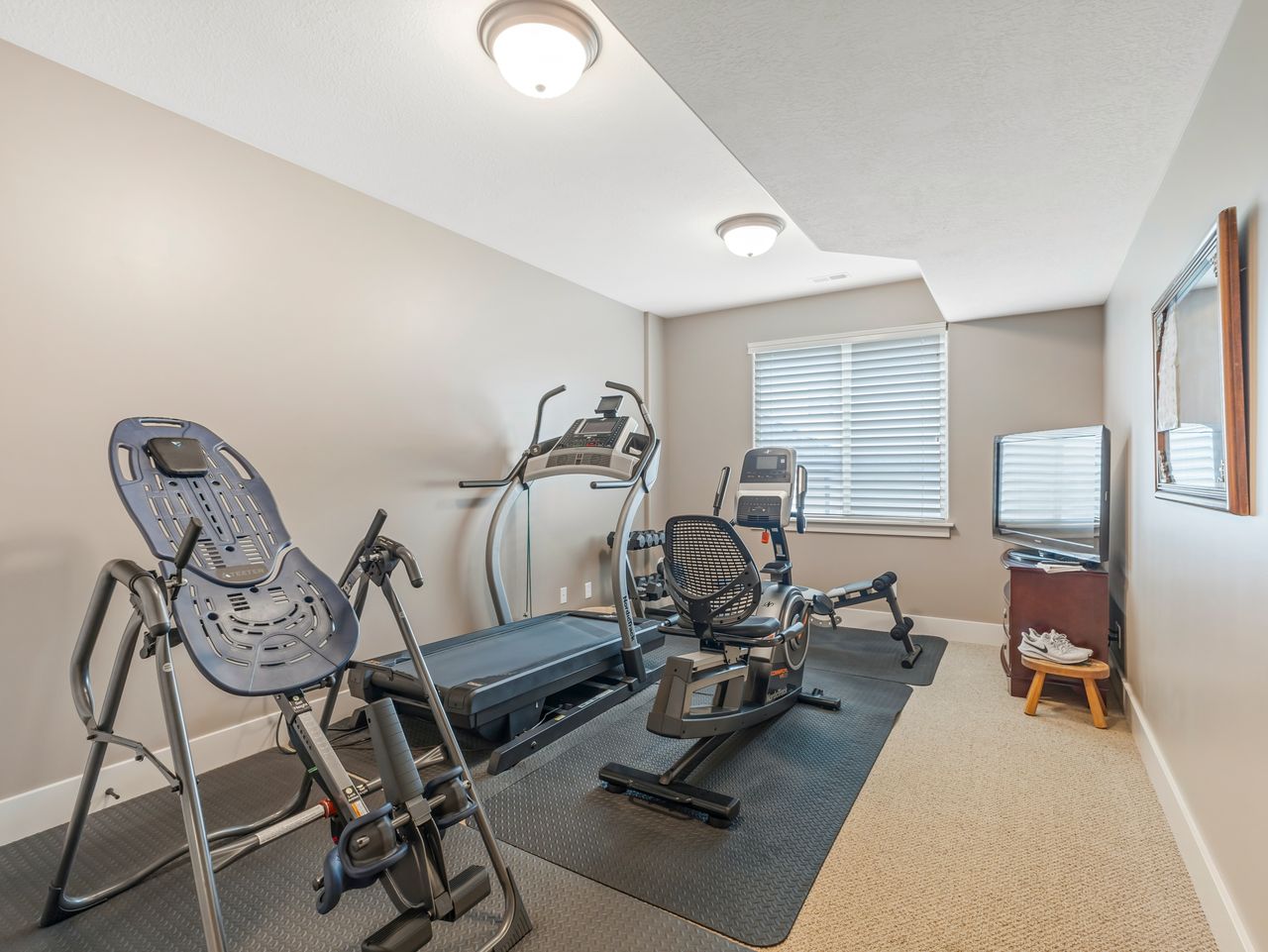 Dedicated fitness space with neutral wall tones and recessed lighting