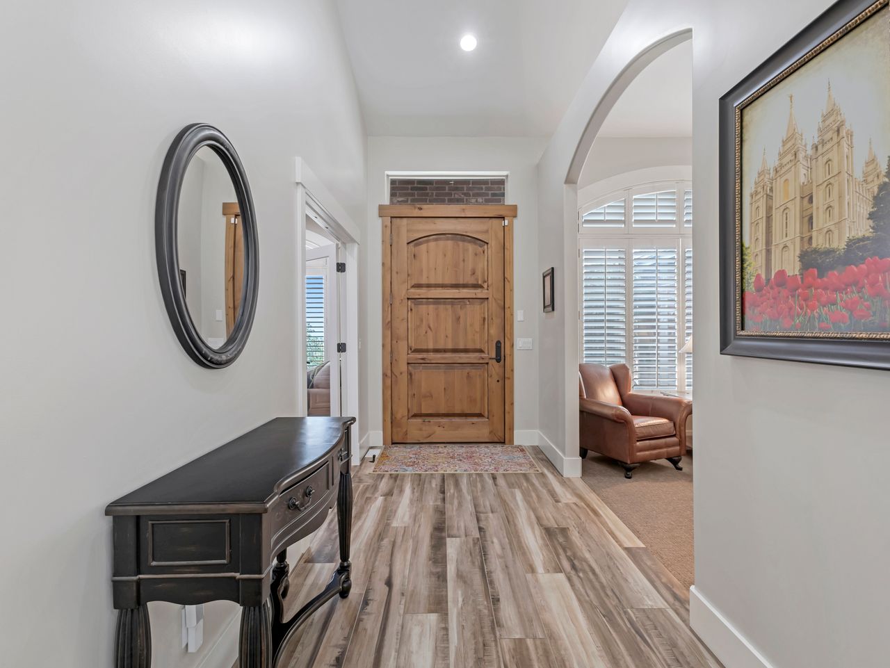 Entryway featuring a wood-panel door, light wood-finish flooring, an arched doorway, and white baseboards