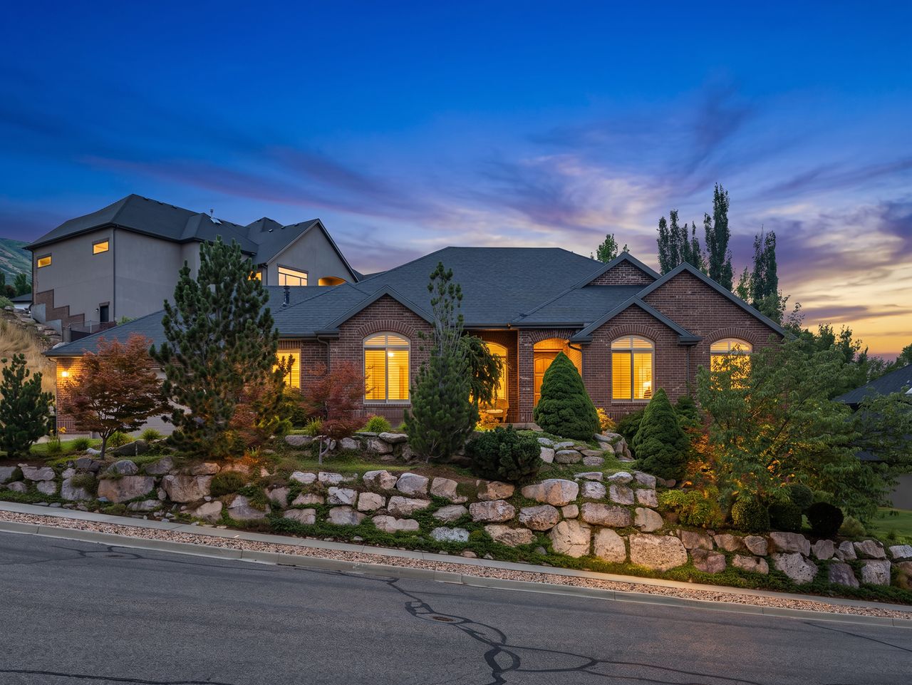 Brick exterior featuring arched windows, a multi-level roofline, and a stone retaining wall