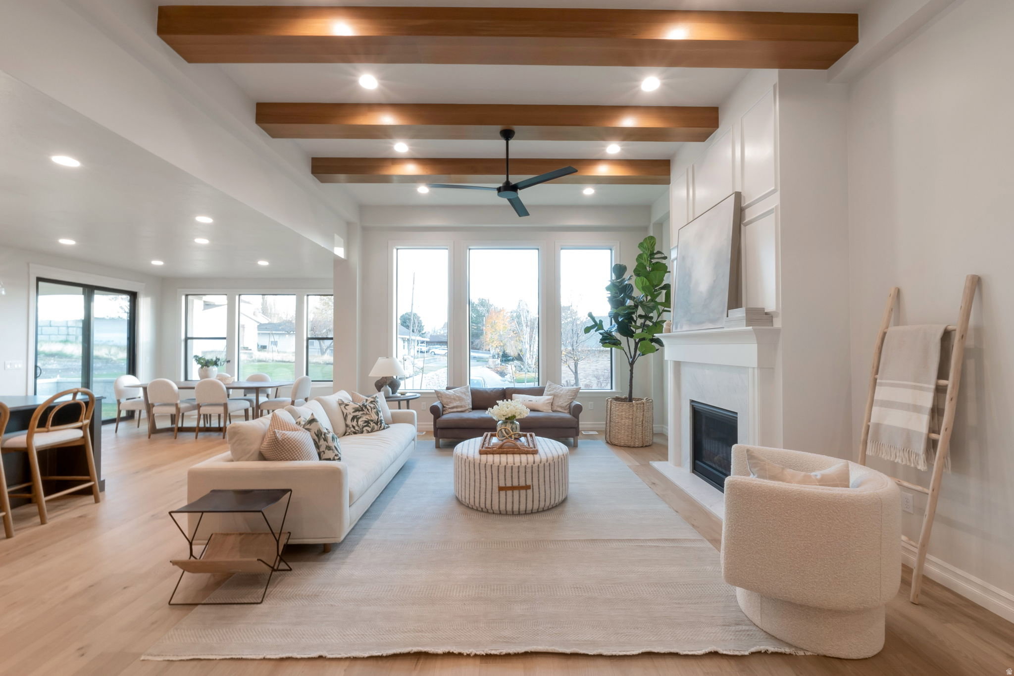 Open concept living space featuring wood-finish flooring, a white-painted fireplace with built-in cabinetry, and a ceiling fan