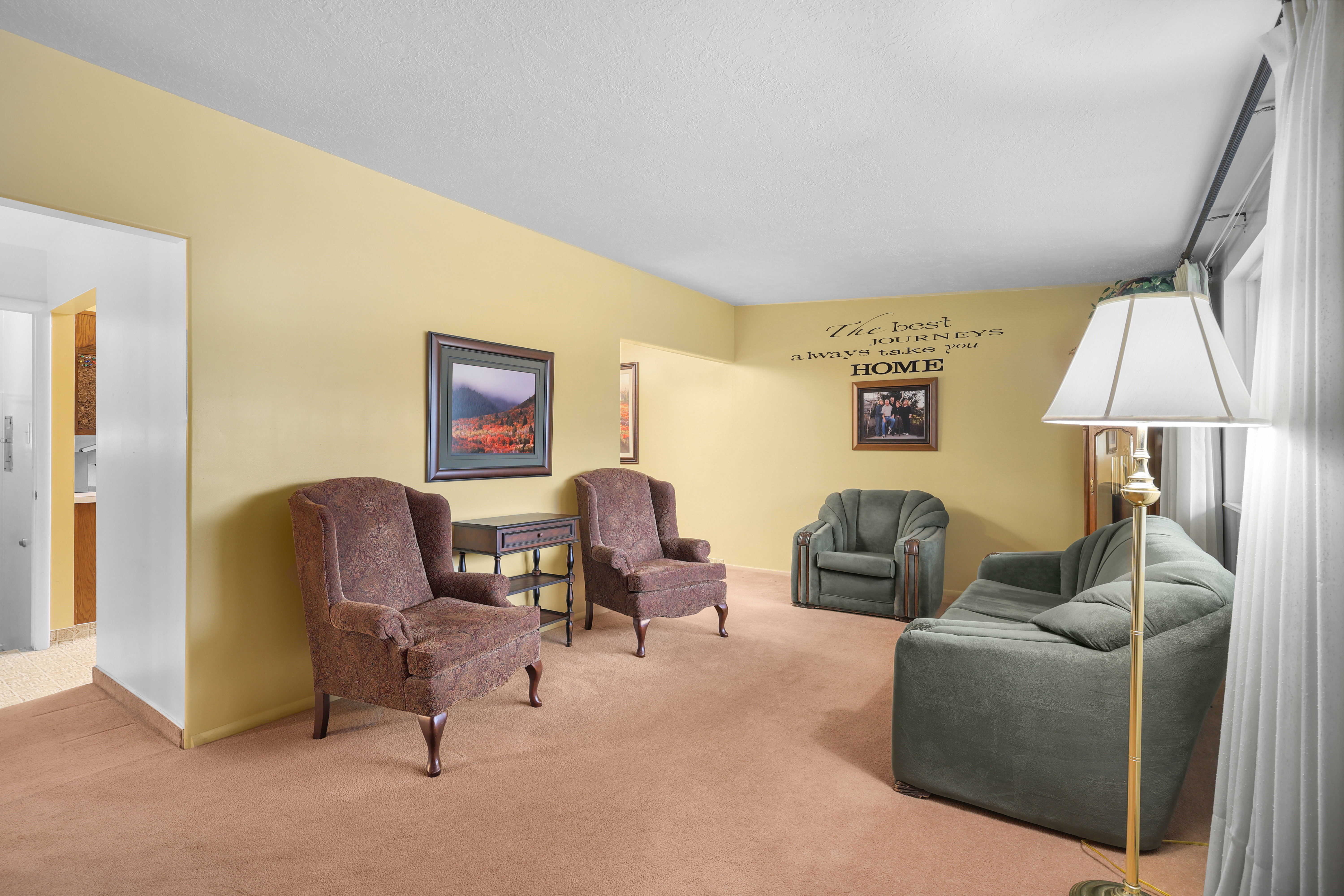 Carpeted living area featuring light yellow painted walls, white trim, and a white ceiling