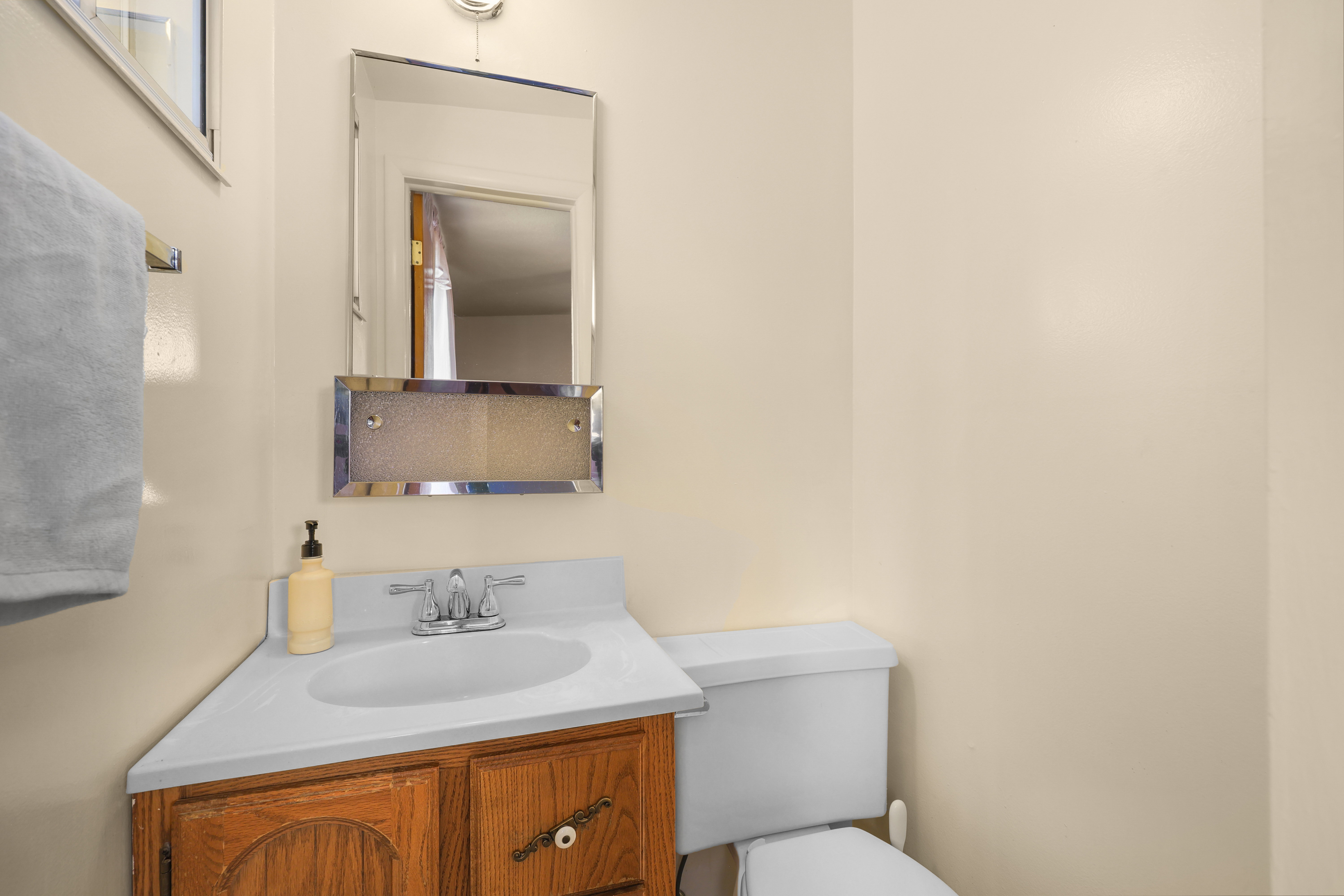 Corner vanity with a white countertop and a wood-finish cabinet